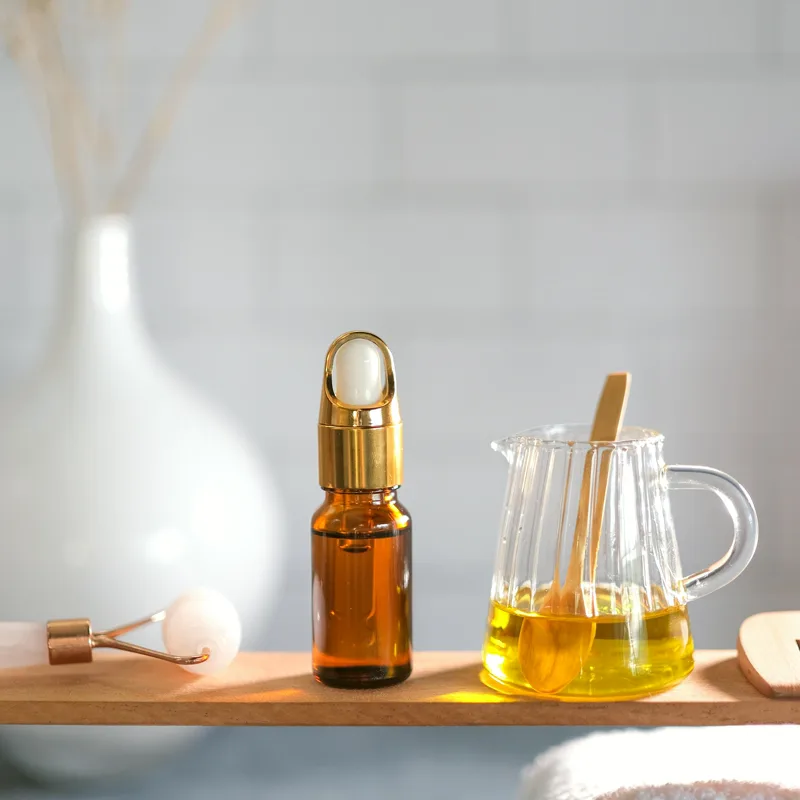 Frasco cuentagotas ámbar y jarrita de cristal con aceite sobre una tabla de madera